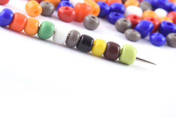 Multi colored Beads spread on white background with needle. Beads with needle . Close up, macro,finishing fashion clothes. make bead necklace, beads for women of fashion,Bead Crochet. Daily Beading. - Photo, Image