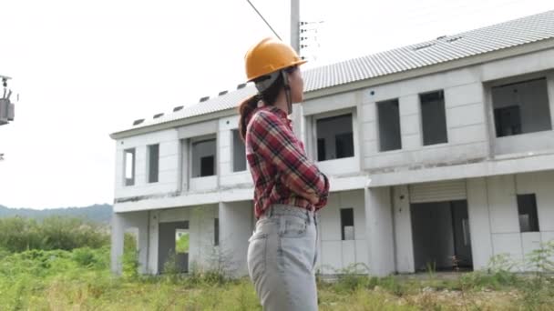 Медленные кадры проверки строительной площадки, азиатская женщина-инженер в шлемах, прогуливающаяся по строительной площадке  - Кадры, видео