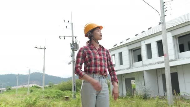 Images lentes de la vérification du site de construction, femme ingénieur asiatique dans les casques marchant autour du site de construction  - Séquence, vidéo