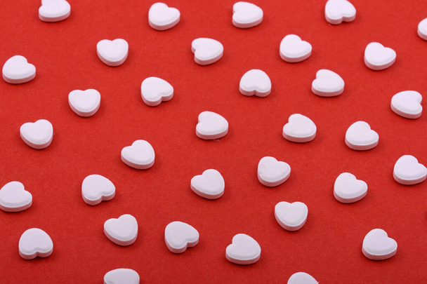 Heart shaped pills on a red background. Medicines that help people. - Фото, изображение