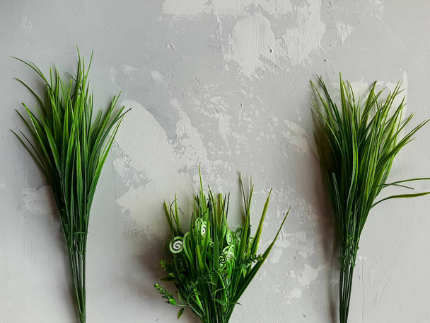 Green grass on gray neutral plaster background - Fotografie, Obrázek