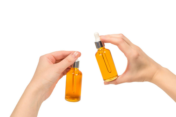 Butelka z olejkiem w ręce kobiety odizolowana na biało. Przestrzeń kopiowania. - Zdjęcie, obraz