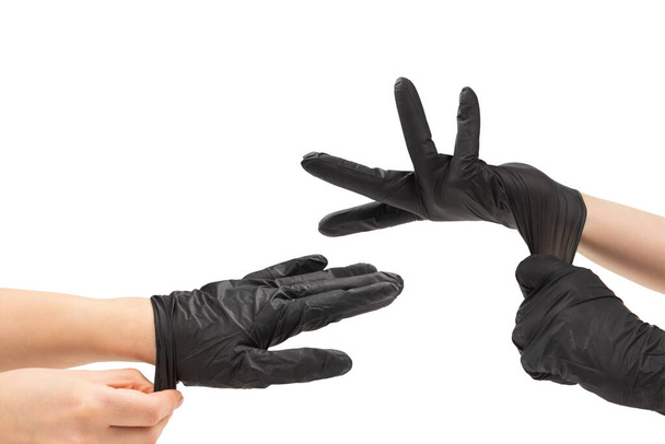 Женщина надевает черные резиновые перчатки. Изолированные на белом. - Фото, изображение