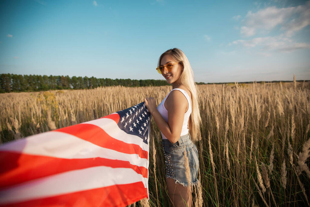 красивая молодая женщина в солнечных очках с американским флагом - Фото, изображение