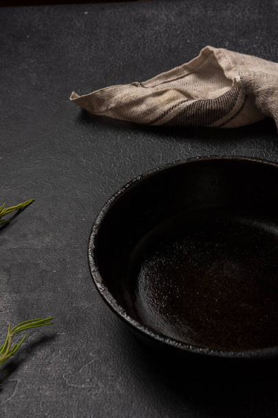 Empty black cast iron frying pan on a dark graphite background - 写真・画像