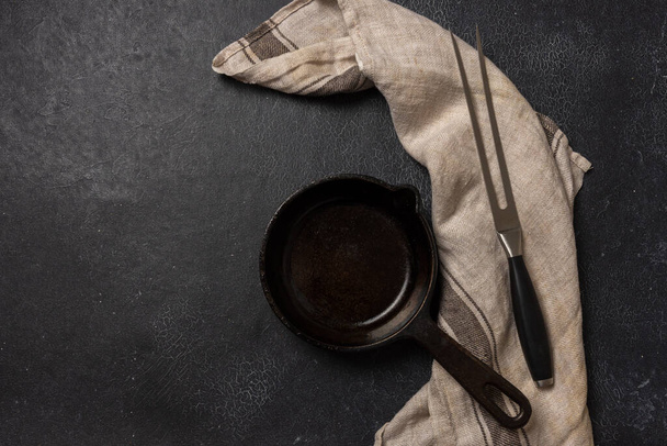 Empty black cast iron frying pan on a dark graphite background - Valokuva, kuva