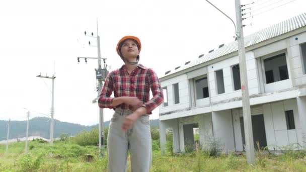 Langzame beelden van het controleren van de bouwplaats, Aziatische vrouwelijke ingenieur in helmen lopen rond de bouwplaats  - Video