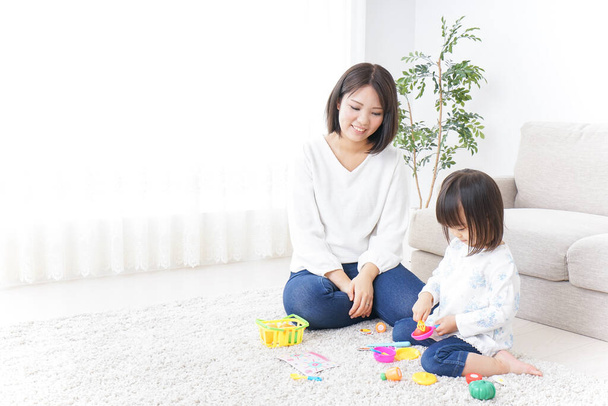 мать и ребенок играют с игрушками на ковре - Фото, изображение