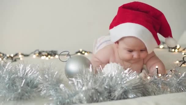 Hyvää joulua joulu ja onnellista uutta vuotta, imeväiset, lapsuus, loma käsite - lähikuva alasti 6 kuukautta vanha vastasyntynyt vauva joulupukki hattu hänen vatsa indeksoi koristeet joulukuusi. - Materiaali, video