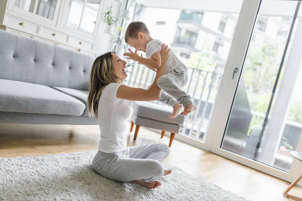 Mother with her son playing in their living room - Photo, Image