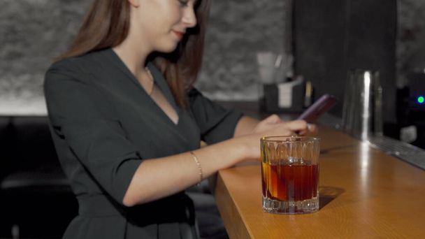 Foto recortada de una mujer tomando una copa de cóctel del mostrador del bar
 - Foto, Imagen