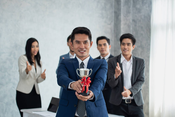 Boldog üzletember tartja a győztes trófeát Sok kéz tapsol mögötte, Üzleti koncepció - Fotó, kép