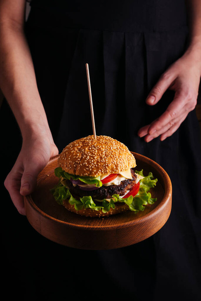 Woman holding a plate with hamburger - Zdjęcie, obraz