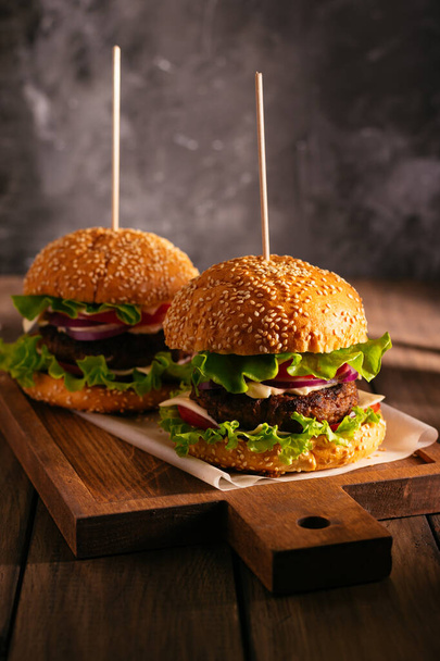 Two burgers on a wooden board - Фото, зображення