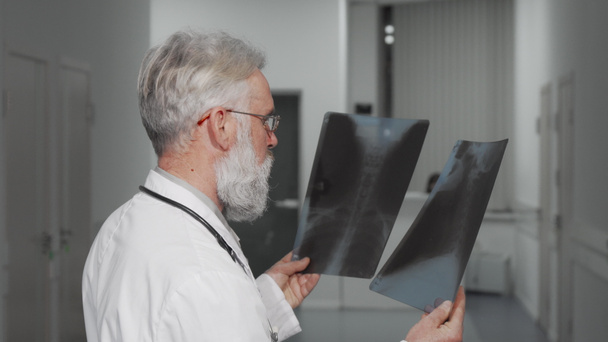 Senior doctor smiling to the camera while examining x-ray scans - Photo, Image