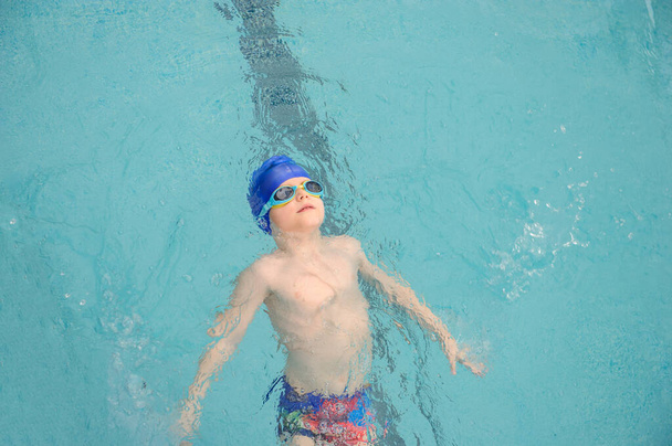 top view egy 7 éves fiú úszás hátúszás hátúszás a medencében - Fotó, kép