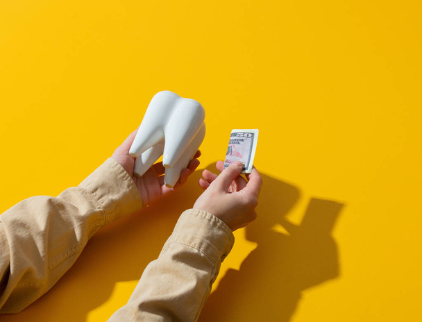 female hand money and tooth on yellow background - Φωτογραφία, εικόνα