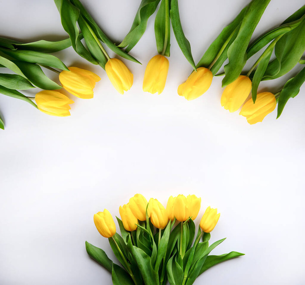 Vista dall'alto di una bella cornice da tulipani gialli su sfondo bianco con spazio per copiare il testo. Carta regalo perfetta - Foto, immagini