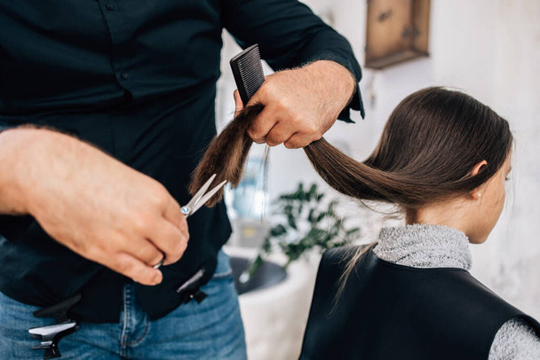 Young girl enjoying at hairstyle treatment while professional hairdresser gently working and cutting her hair. - Foto, Imagem
