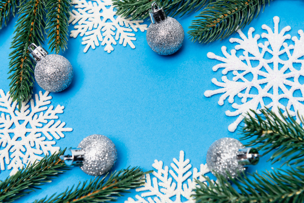 top view of snowflakes, silver baubles and spruce on blue background - 写真・画像