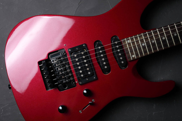 Červená elektrická kytara na tmavém betonovém pozadí, detailní, selektivní zaměření. pohled shora. - Fotografie, Obrázek