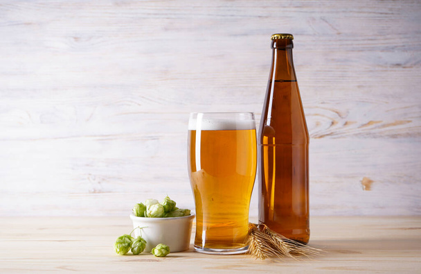 Хмель и светлое пиво на деревянном фоне - Фото, изображение