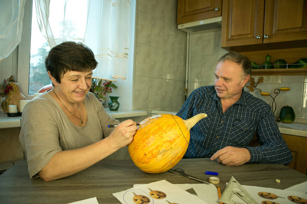 Making Jack O'Lantern at home. The process of creating a Jack O'Lantern theme template. A man and a woman are preparing a pumpkin for carving. - Photo, Image
