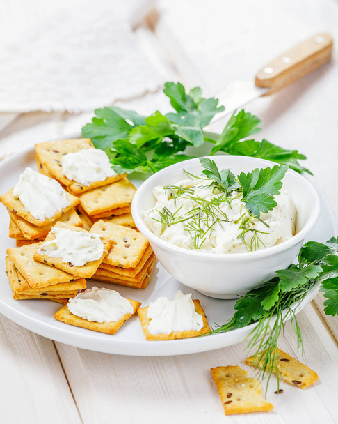 queso crema con galletas saladas sobre fondo blanco - Foto, Imagen