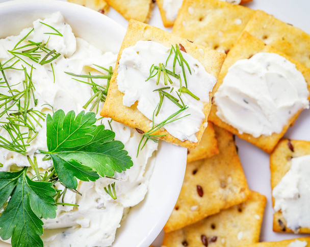 queso crema con galletas saladas sobre fondo blanco - Foto, imagen
