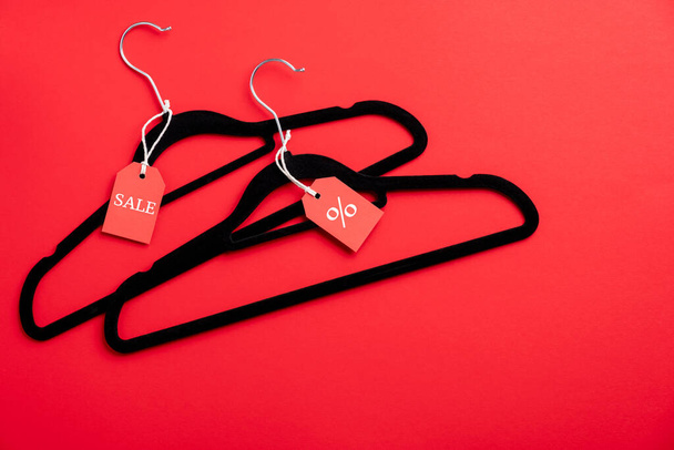 Two coat hangers on red background. Flat lay, top view. Black Friday sale, discount, outlet in fashion store concept. - Zdjęcie, obraz