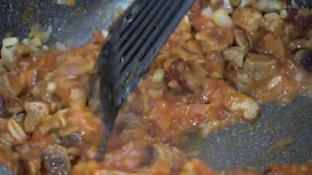 Clipe de vídeo 4K de molho de cozinha, molho ou molho com pedaços de carne, pasta de tomate e legumes em close-up. Guisado de legumes com carne é misturado com uma espátula. O processo de cozinhar comida para jantar - Filmagem, Vídeo