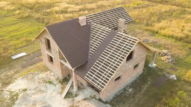 Letecký pohled na nedokončený dům s dřevěnou střešní konstrukcí potaženou kovovými dlaždicemi ve výstavbě. - Záběry, video
