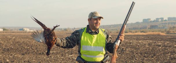 Chasseur de canards avec fusil de chasse marchant dans une prairie. - Photo, image