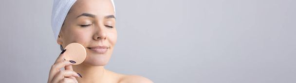 Schönheitsporträt einer Frau in weißem Handtuch auf dem Kopf mit einem Schwamm für einen Körper angesichts eines rosafarbenen Herzens. Reinigung der Haut Öko-Kosmetik Wellness-Entspannungskonzept. - Foto, Bild