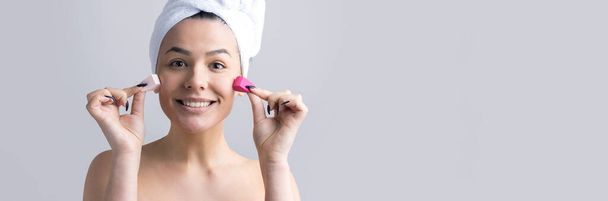 Beauty portrait of woman in white towel on head with a sponge for a body in view of a pink heart. Skincare cleansing eco organic cosmetic spa relax concept. - Photo, Image