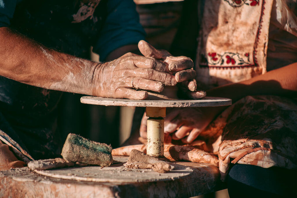 Un vasaio esperto insegna ad un apprendista a lavorare con argilla e ruota di un vasaio - Foto, immagini
