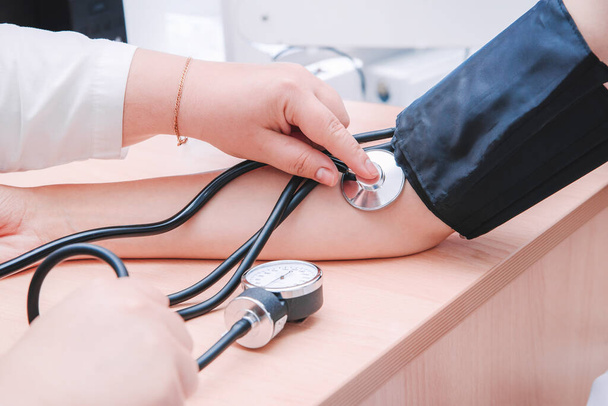 A nurse, doctor, or healthcare professional measures the patient's blood pressure with a hand-held tonometer horizontal close-up photo - Foto, Bild