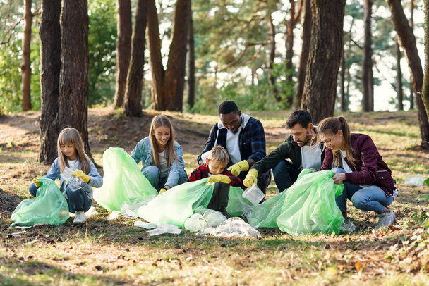 Group of international multi aged volunteers keep nature clean and picking up garbage from the forest. Ecology concept. - 写真・画像