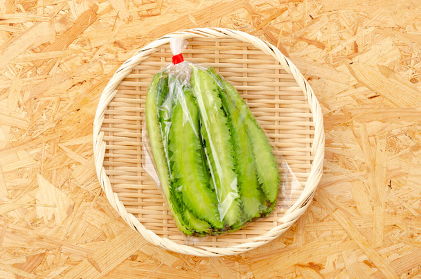 Feijão alado fresco em saco plástico em uma peneira de bambu em um fundo de madeira compensada - Foto, Imagem