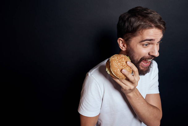 Homem comendo hambúrguer fast food restaurante Gourmet comendo fundo escuro - Foto, Imagem