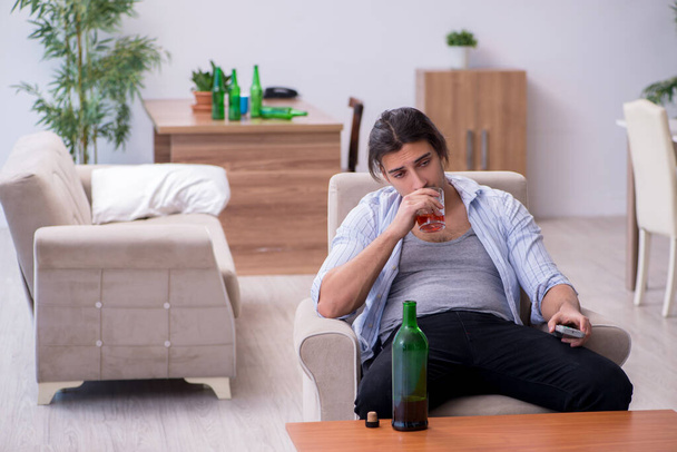 Giovane maschio alcolizzato guardare la tv dopo la festa - Foto, immagini