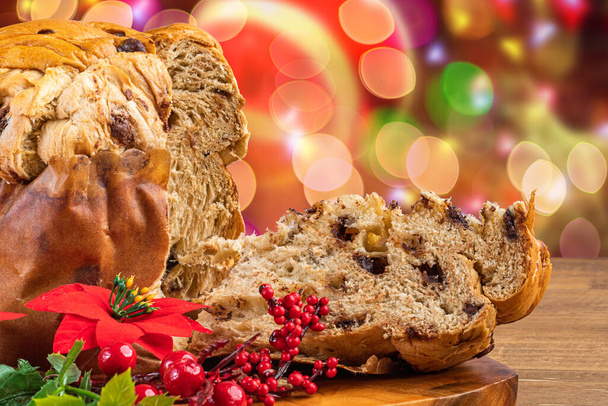Panettone with chocolate, traditional Italian dessert cake for Christmas. Flashing lights and blurred decorations in the background. - Photo, Image