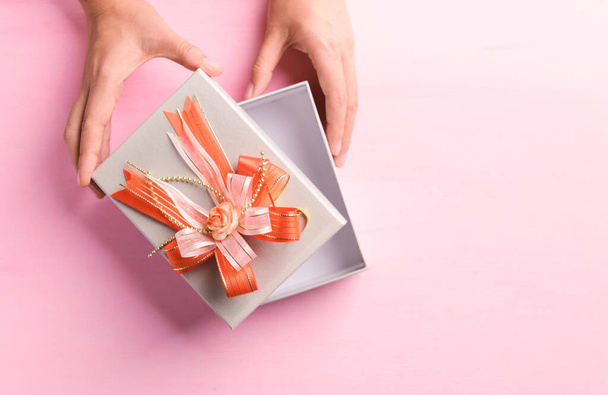Caja de regalo con cinta naranja abierta a mano sobre fondo rosa, regalo para regalar en día especial, Vista superior - Foto, Imagen