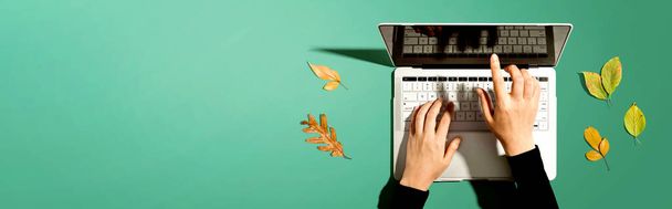 Autumn leaves with person using a laptop computer - 写真・画像