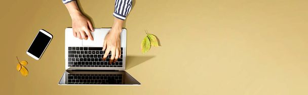 Autumn leaves with person using a laptop computer - 写真・画像
