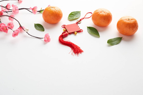 Gelukkig Chinees Nieuwjaar 2021 of Maan Nieuwjaar decoratie festival top view Hanger Ornamenten Knoop en Roze kers met Oranje fruit op Witte houten tafel - Foto, afbeelding