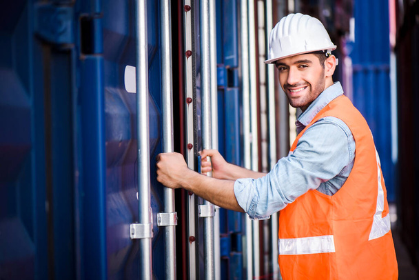 Young confident Caucasian man engineer standing with box container background and check for control loading containers box from Cargo freight ship for import and export, transport - Fotoğraf, Görsel