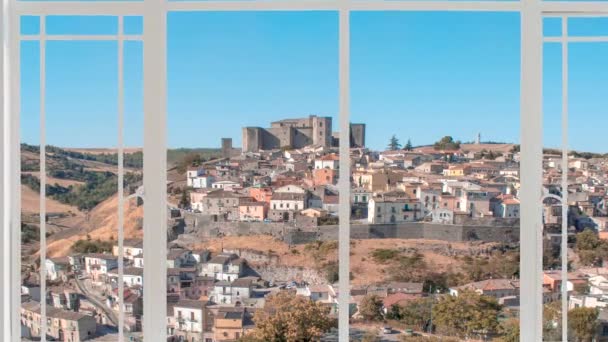 Paysage urbain de Melfi vu depuis une fenêtre blanche alors que les oiseaux volent. On voit le village avec château médiéval en arrière-plan sur la colline et la campagne autour d'elle.  - Séquence, vidéo