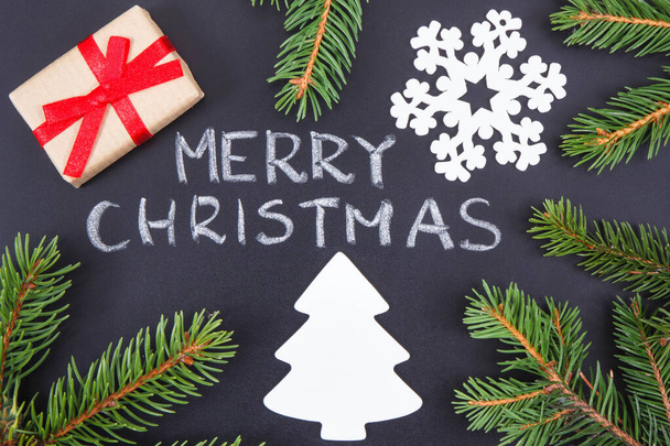 Aufschrift Frohe Weihnachten, verpackte Geschenke mit Schleife, Christbaumform und grünen Fichtenzweigen. Dekoration für Weihnachten - Foto, Bild