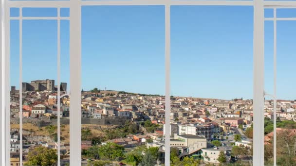 Melfi Stadtbild aus einem weißen Fenster gesehen, während Vögel fliegen. Man sieht das Dorf mit der mittelalterlichen Burg im Hintergrund auf dem Hügel und die umliegende Landschaft.  - Filmmaterial, Video